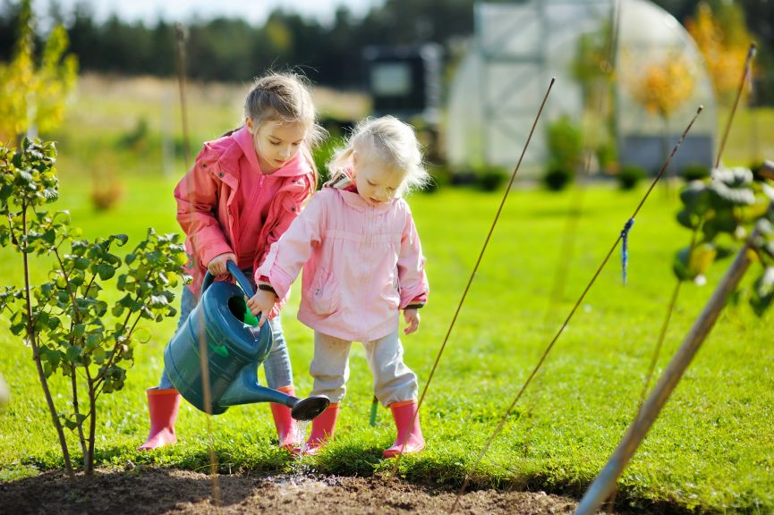 children watering plants in garden learning responsibility